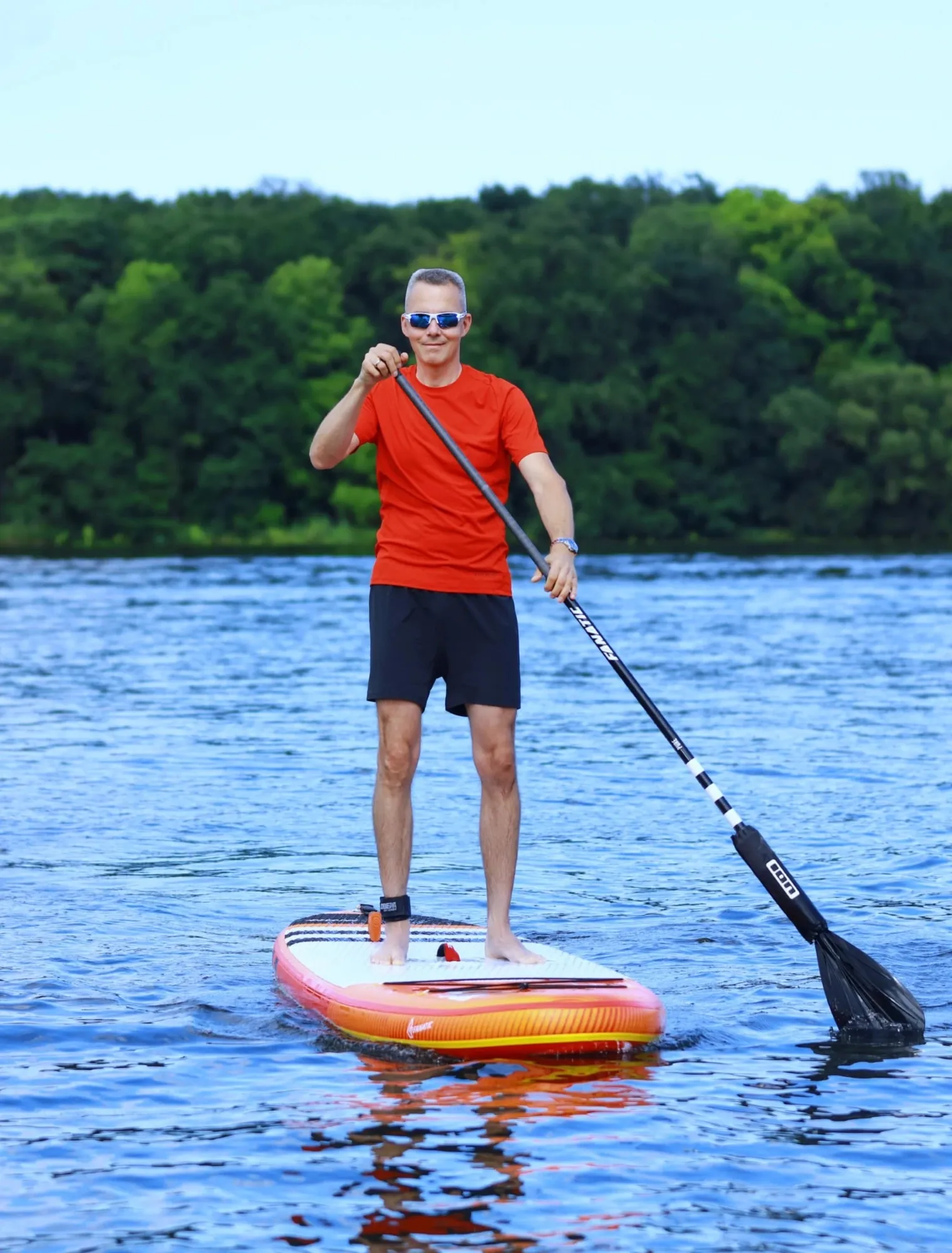 Stand-up-Paddler mit Sportsonnenbrille auf dem See